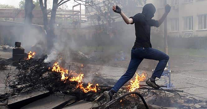 A masked man jumps over a burning barricade in front of the police headquarters in the southeastern port city of Mariupol. Ukrainian forces attacked the police headquarters in Mariupol in an attempt to drive out pro-Russian militants. (Reuters)</em) A masked man jumps over a burning barricade in front of the police headquarters in the southeastern port city of Mariupol. Ukrainian forces attacked the police headquarters in Mariupol in an attempt to drive out pro-Russian militants. (Reuters)</em)