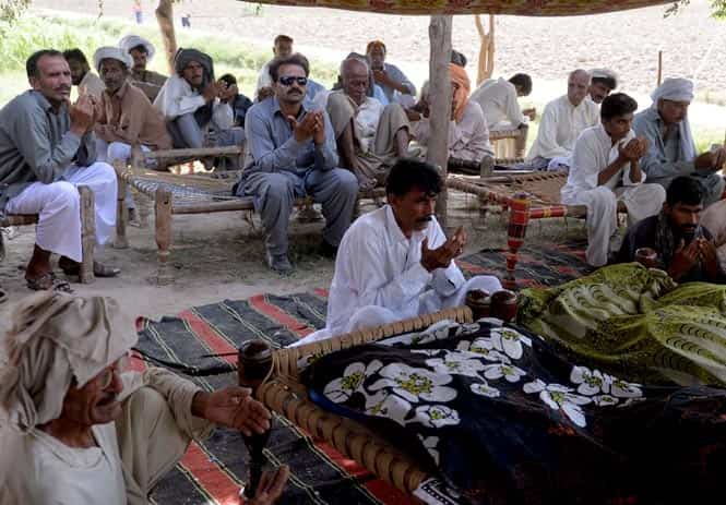 Mohammad Iqbal prays alongside relatives for his wife Farzana. (AFP Photo)</em> 
</div)