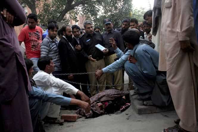 Police collect evidence near the body of Farzana Iqbal, who was killed by family members, near the Lahore High Court building in Lahore. (Reuters Photo)</em> 
</div)