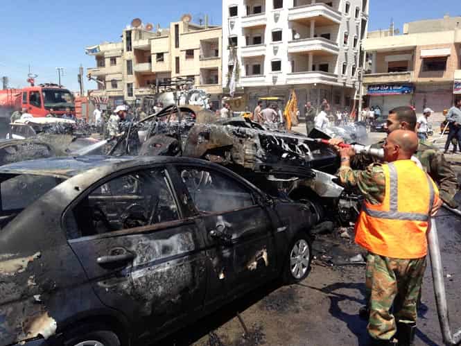 Emergency teams extinguish a fire at the site of a car bomb attack in a regime-held area in Syria's central city of Homs, that left at least 10 people dead and 22 injured, according to the governor of Homs. (AFP Photo)</em)