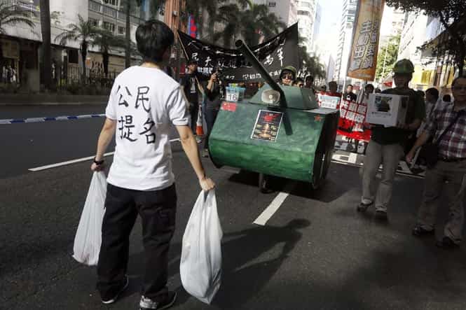 A protester stands in front of a mock tank to symbolise the man blocking a line of tanks at the 1989 pro-democracy movement in Beijing. (AP photo) 
</div)