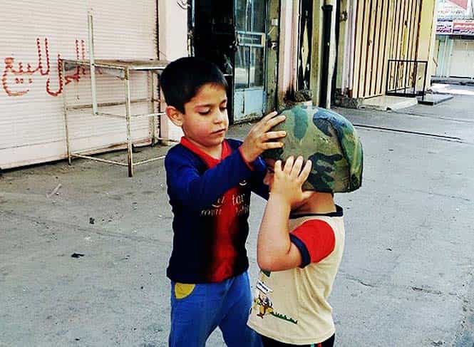 Children play with an Iraqi Army helmet left behind after militants from the al Qaeda-inspired Islamic State of Iraq and the Levant took over the northern city of Mosul, Iraq. (AP Photo, File)</em) Children play with an Iraqi Army helmet left behind after militants from the al Qaeda-inspired Islamic State of Iraq and the Levant took over the northern city of Mosul, Iraq. (AP Photo, File)</em)