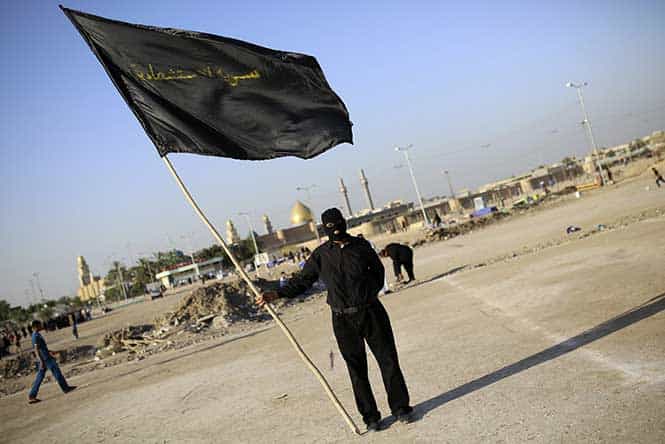 A member of the Mehdi Army loyal to Shi'ite cleric Moqtada al-Sadr holds a black flag that reads, "suicide unit" during a military-style training in the holy city of Najaf. (Reuters Photo)</em) A member of the Mehdi Army loyal to Shi'ite cleric Moqtada al-Sadr holds a black flag that reads, "suicide unit" during a military-style training in the holy city of Najaf. (Reuters Photo)</em)