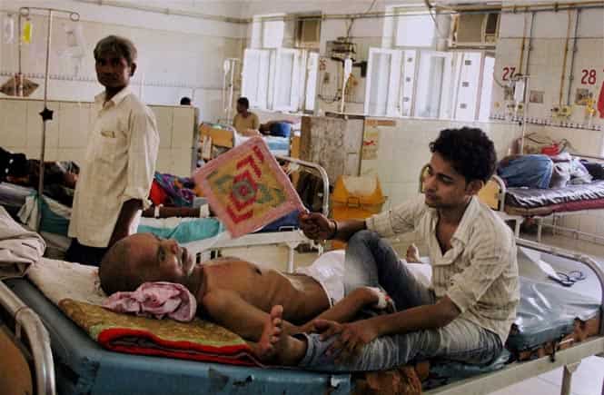 A boy uses a hand fan to comfort a patient during electricity outage at Swaroop Rani Nehru Hospital on a hot summer day in Allahabad. (PTI Photo)</em> 
</div)