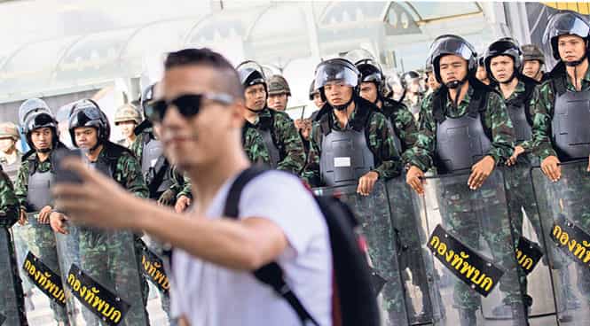 A tourist stops to take a selfie with Thai soldiers outside the Bangkok Art Culture Centre in Bangkok, Thailand. (AP Photo)</font></em) A tourist stops to take a selfie with Thai soldiers outside the Bangkok Art Culture Centre in Bangkok, Thailand. (AP Photo)</font></em)