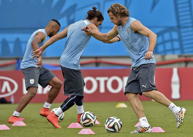 Uruguay's forward Diego Forlan (R), defender Martin Caceres and midfielder Alvaro Pereira (L) exercise with balls during a training session at Dunas Arena in Natal, Rio Grande do Norte, Brazil on the eve of a FIFA World Cup Group D football match between Italy and Uruguay. (AFP Photo)</em)