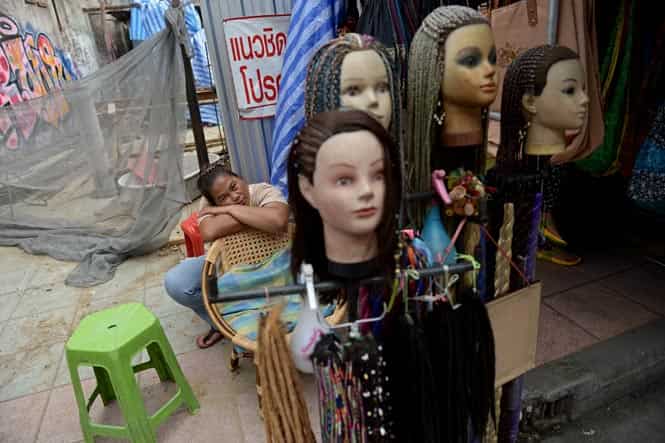 This picture taken on May 29, 2014 shows a street vendor resting next to braided mannequin heads as she waits for customers at the famous tourist district of Khao San road in Bangkok. Thailand's once-booming tourism industry is scrambling to arrest a slump in foreign visitor numbers after a military coup and a night-time curfew tarnished its reputation as the "Land of Smiles". (AFP Photo)</em) This picture taken on May 29, 2014 shows a street vendor resting next to braided mannequin heads as she waits for customers at the famous tourist district of Khao San road in Bangkok. Thailand's once-booming tourism industry is scrambling to arrest a slump in foreign visitor numbers after a military coup and a night-time curfew tarnished its reputation as the "Land of Smiles". (AFP Photo)</em)