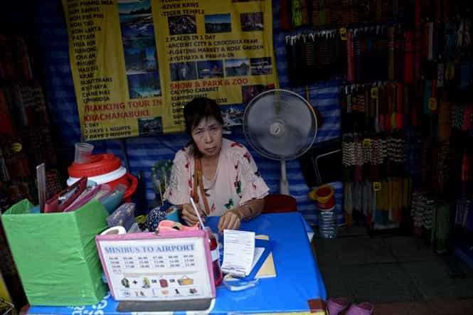 A tourism operator waits for customers at her street-side shop at the famous tourist district of Khao San road in Bangkok. (AFP Photo) </em) A tourism operator waits for customers at her street-side shop at the famous tourist district of Khao San road in Bangkok. (AFP Photo) </em)