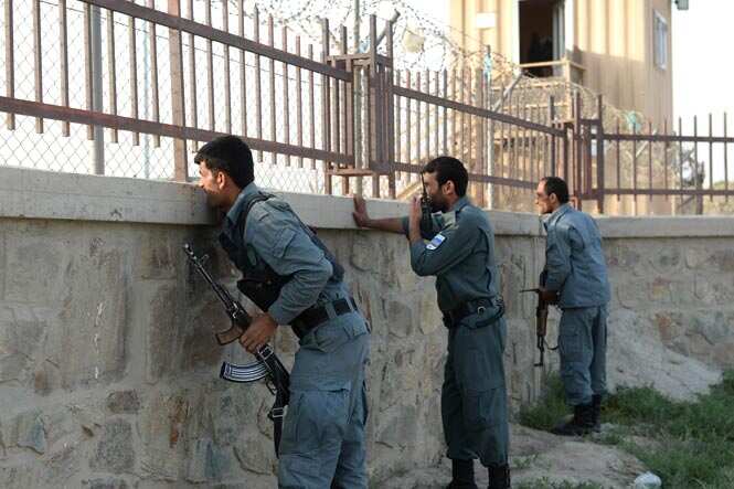Afghan policemen take cover near the site of a suicide attack in front of Kabul's military airport.(AFP Photo)</em) Afghan policemen take cover near the site of a suicide attack in front of Kabul's military airport.(AFP Photo)</em)