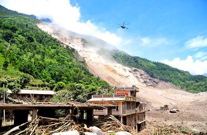 A Nepalese Army helicopter flies over the site of a landslide during a rescue operation in Sindhupalchowk area, about 120 kilometers east of Katmandu, Nepal. (AP Photo)</em) A Nepalese Army helicopter flies over the site of a landslide during a rescue operation in Sindhupalchowk area, about 120 kilometers east of Katmandu, Nepal. (AP Photo)</em)