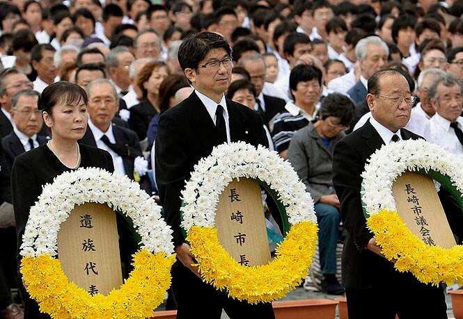Nagasaki mayor Tomihisa Taue, center, carries a wreath of flowers during a ceremony at Nagasaki Peace Park in Nagasaki, southern Japan to mark the 69th anniversary of the atomic bombing. (AP/PTI photo) 
</div)