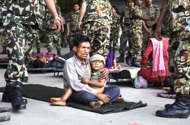 A man sits with a child on his lap waiting for ambulances after being evacuated at the airport in Kathmandu, Nepal on April 27, 2015. (AP Photo/Altaf Qadri) A man sits with a child on his lap waiting for ambulances after being evacuated at the airport in Kathmandu, Nepal on April 27, 2015. (AP Photo/Altaf Qadri)