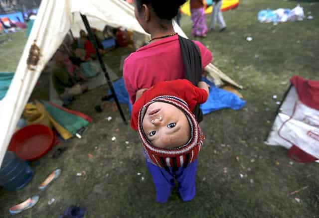 An earthquake victim carries her baby on her back as she stands outside her makeshift shelter on open ground in the early hours in Kathmandu, Nepal on April 28, 2015. (Reuters Photo/Adnan Abidi) An earthquake victim carries her baby on her back as she stands outside her makeshift shelter on open ground in the early hours in Kathmandu, Nepal on April 28, 2015. (Reuters Photo/Adnan Abidi)