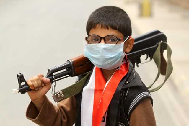 A boy wearing a surgical mask holds a weapon in Sanaa. Reuters Photo A boy wearing a surgical mask holds a weapon in Sanaa. Reuters Photo