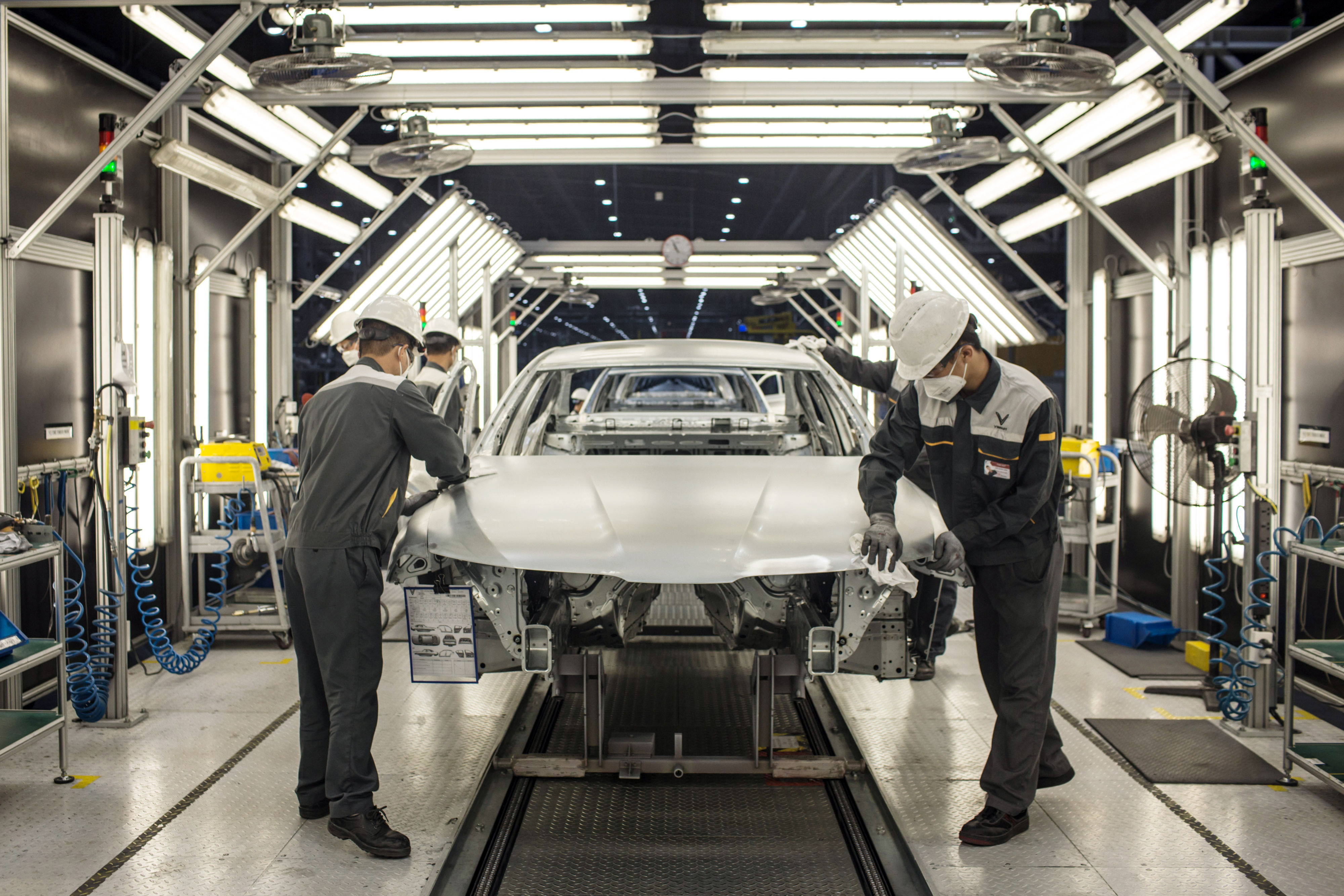 Workers clean the hood of a body frame of a Vinfast Lux A2.0 sedan in the body shop area of the automaker's factory in Haiphong, Vietnam. Workers clean the hood of a body frame of a Vinfast Lux A2.0 sedan in the body shop area of the automaker's factory in Haiphong, Vietnam.