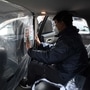 A worker installs a sticker reminding people about the COVID 19 coronavirus on a plastic sheet separating the driver and passenger compartments in a car at a disinfection station for Chinese ride hailing company Didi, in Beijing. (AFP)