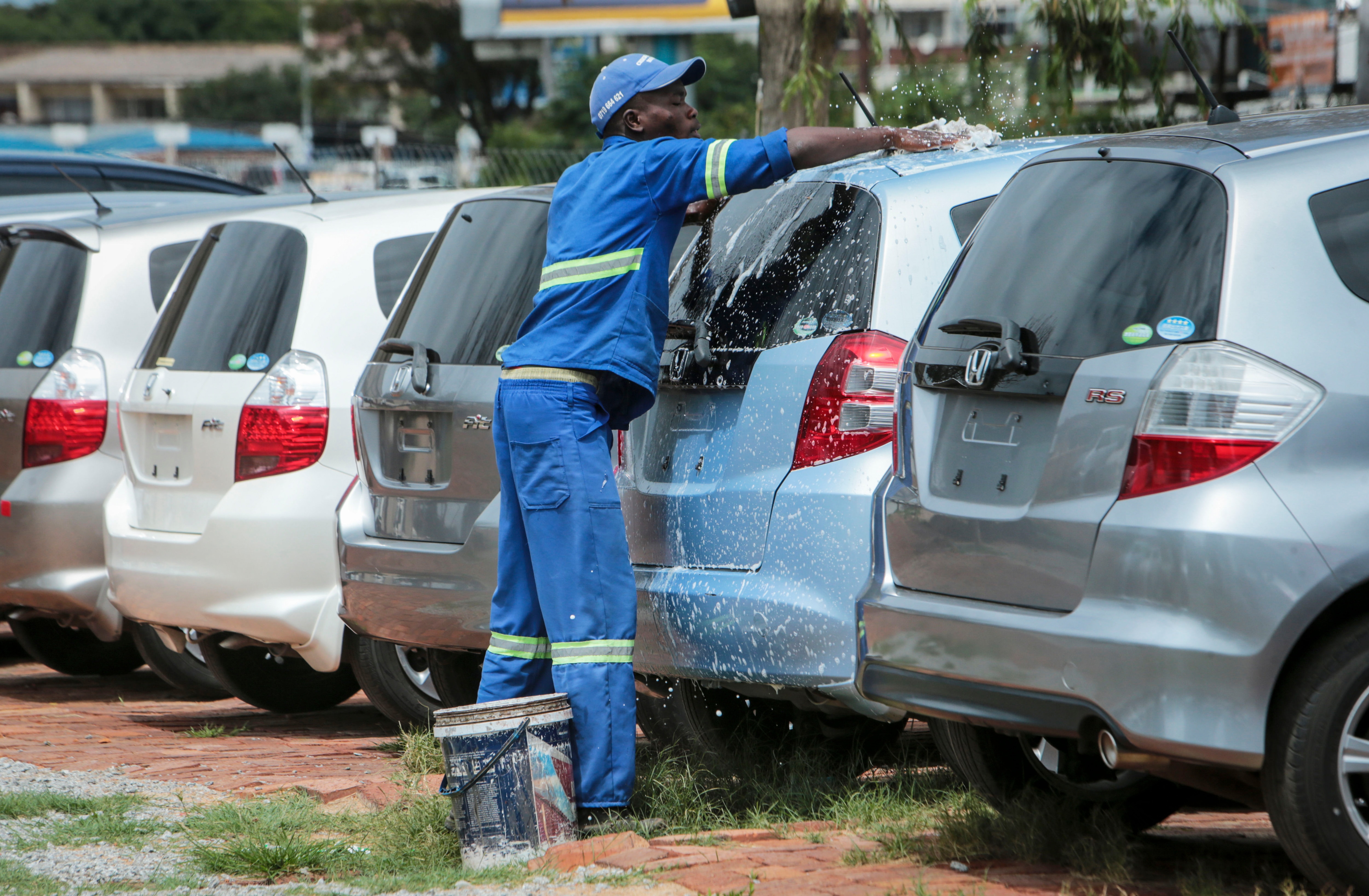 In this photo taken Tuesday, Feb. 25, 2020, a worker washes used cars for sale in the capital Harare, Zimbabwe.