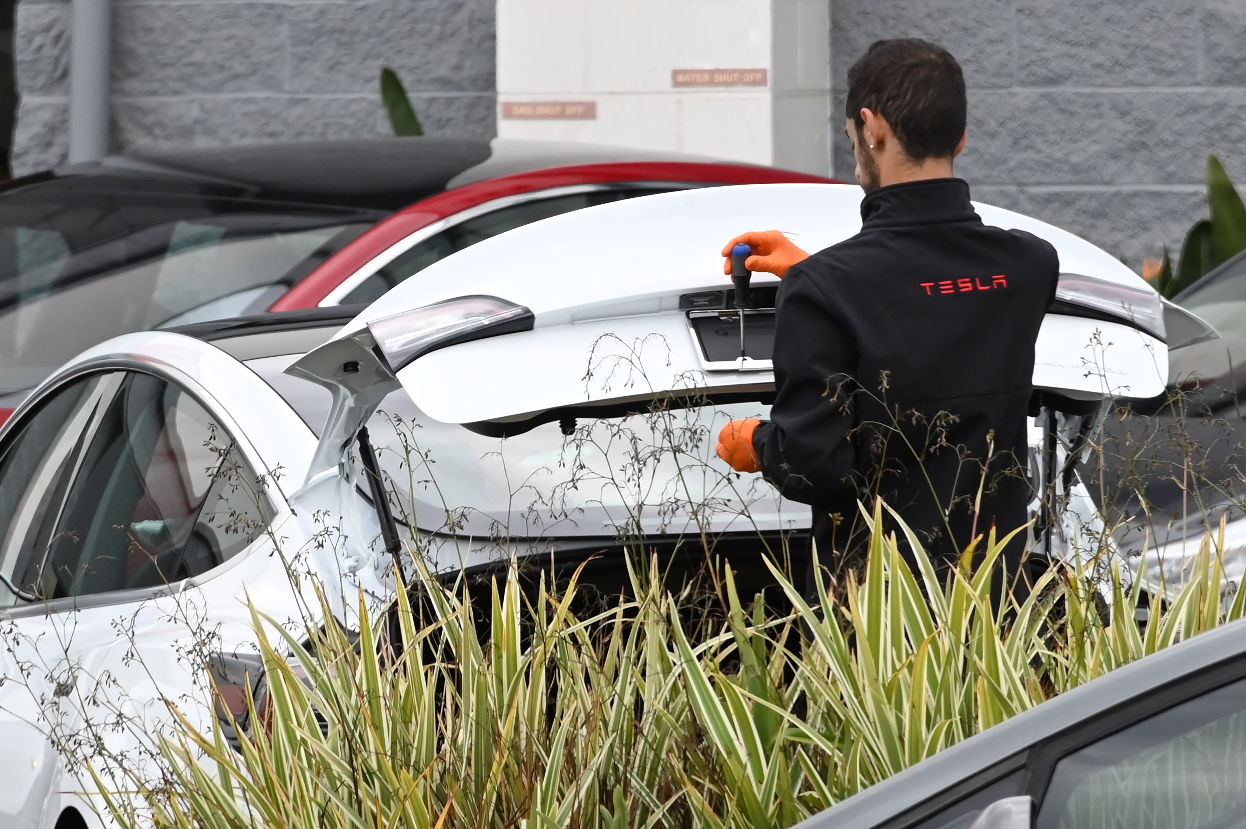 A Tesla employee works on a license plate frame outside a Tesla showroom in Burbank, California.