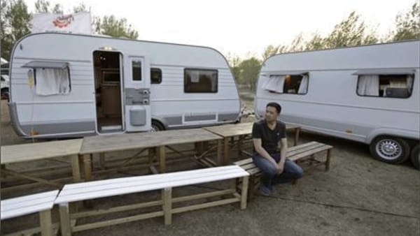 A man sits on a bench in front of recreational vehicles (RVs) during a camping trip at a RV park on the outskirts of Beijing. (File photo) (REUTERS)