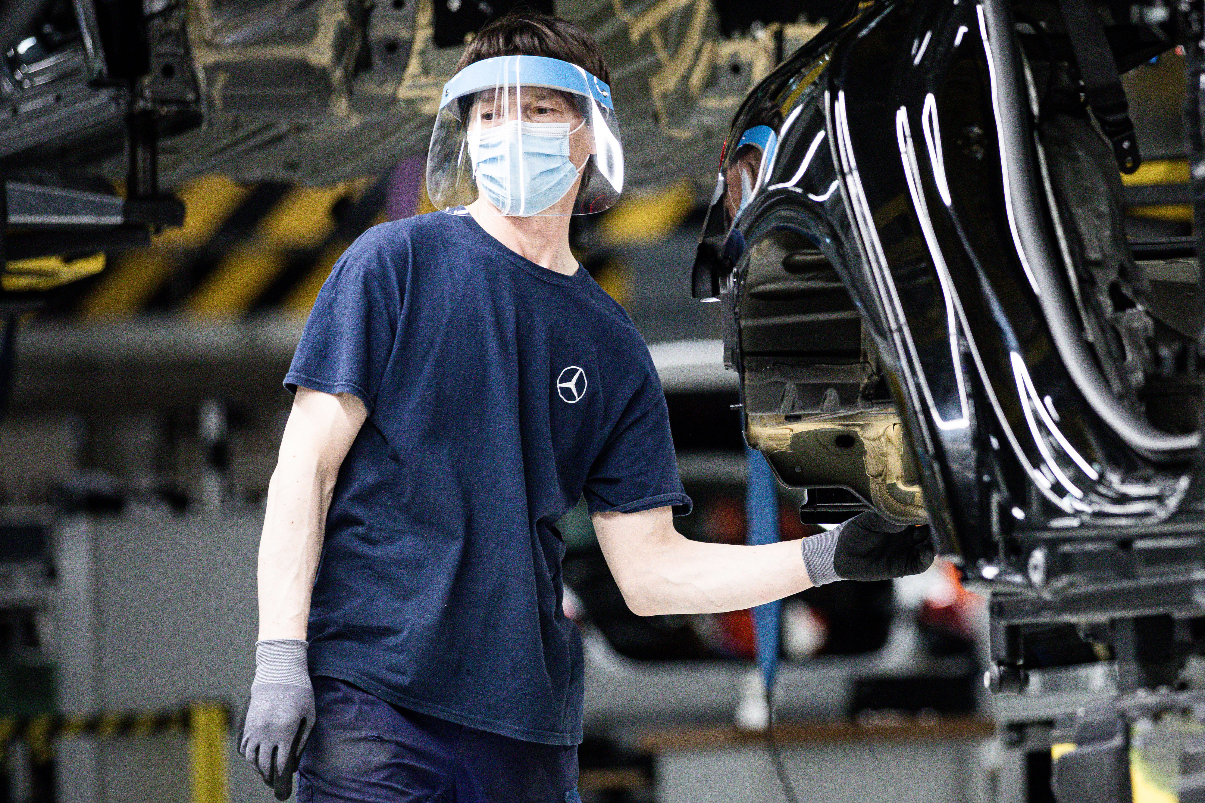 A worker wears a protective face mask and shield on the assembly line inside the Mercedes-Benz AG automobile plant, operated by Daimler AG, in Kecskemet, Hungary.