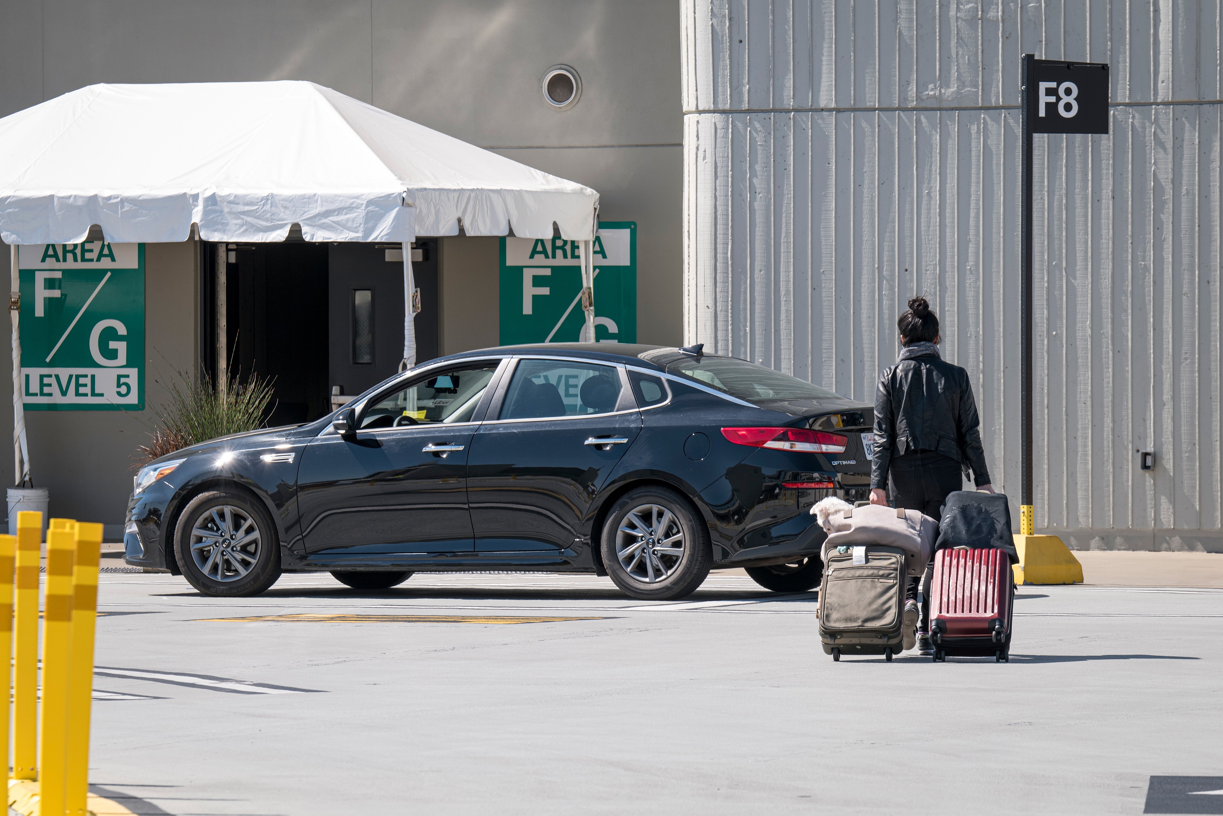 A traveler pulls suitcases towards a ride-sharing car at San Francisco International Airport in San Francisco, California, U.S., on Monday.