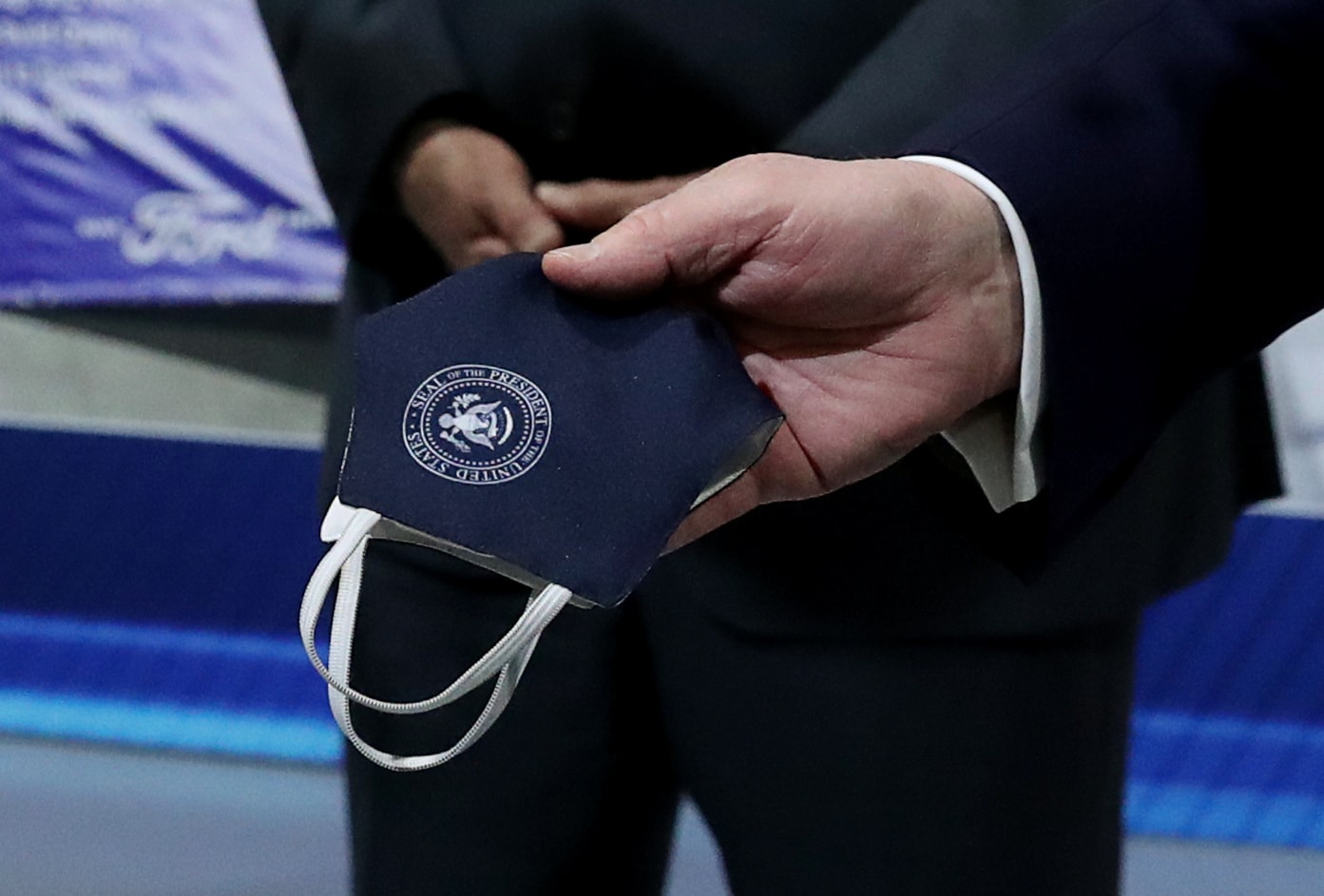 Trump holds a protective face mask with a presidential seal on it that he said he had been wearing earlier in his tour at the Ford Rawsonville Components Plant.
