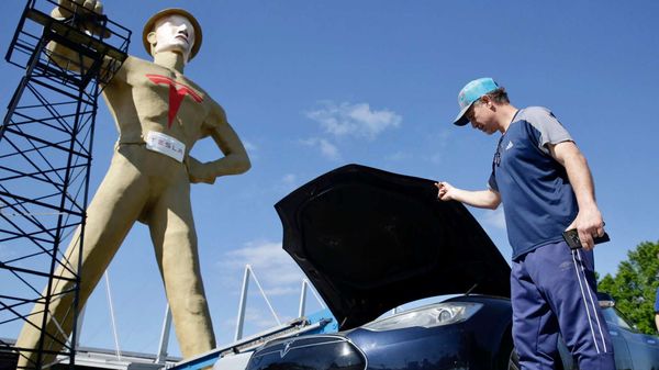 File photo: A Tesla Model S owner opens the hood of his EV in front of the Golden Driller. an iconic Golden Driller statue in Tulsa in Oklahoma.