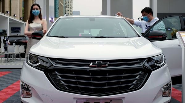 A model wearing a face mask following the coronavirus disease (Covid-19) outbreak stands next to a Chevrolet vehicle at a sales event in China. (REUTERS)