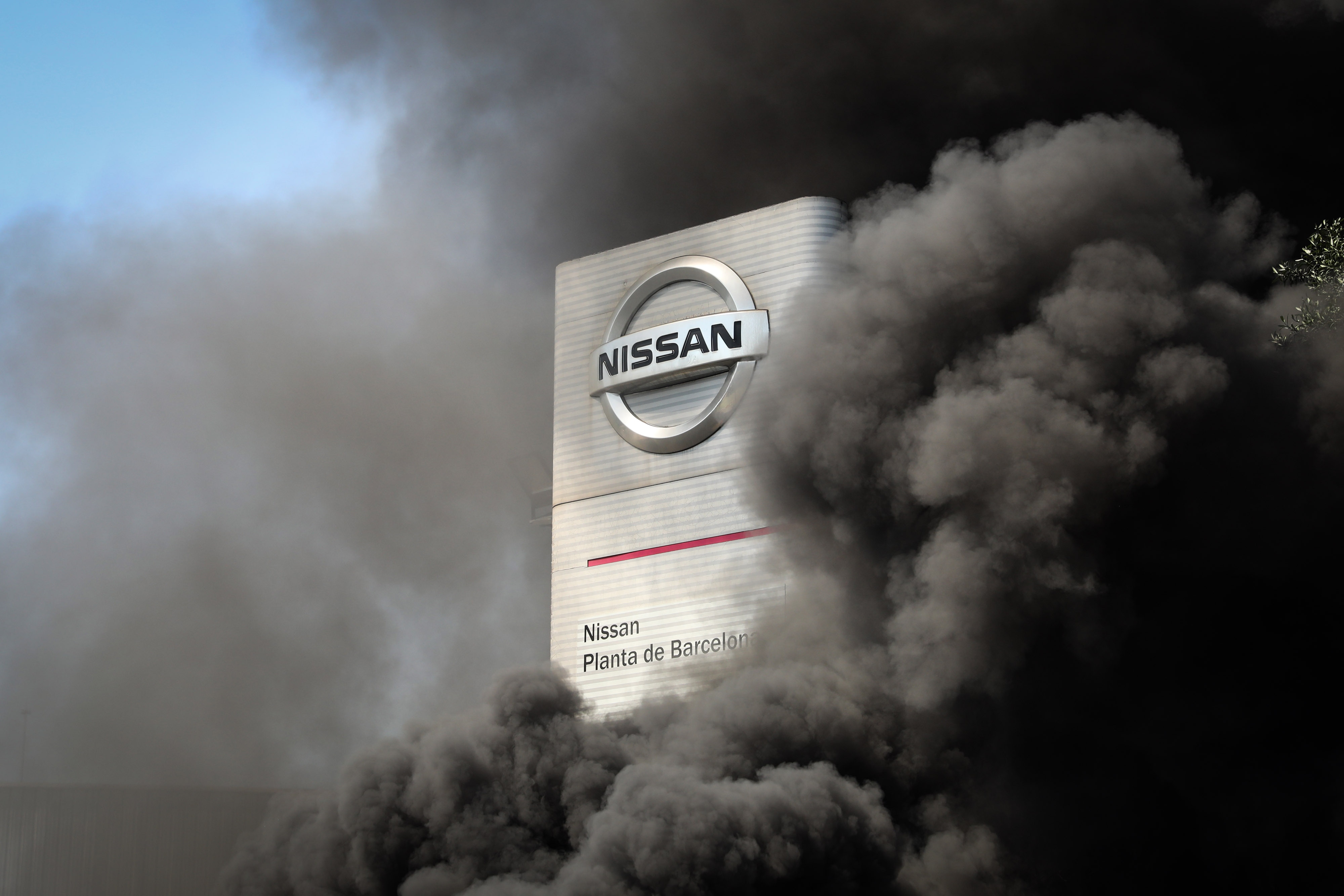 File photo: Smoke from burning tires lit by demonstrators cover a logo outside the Nissan Motor Co. plant in Barcelona, Spain, on Thursday, May 28, 2020. Nissan said it intends to close its Barcelona plant, in addition to the one it is planning to shutter in Indonesia. 