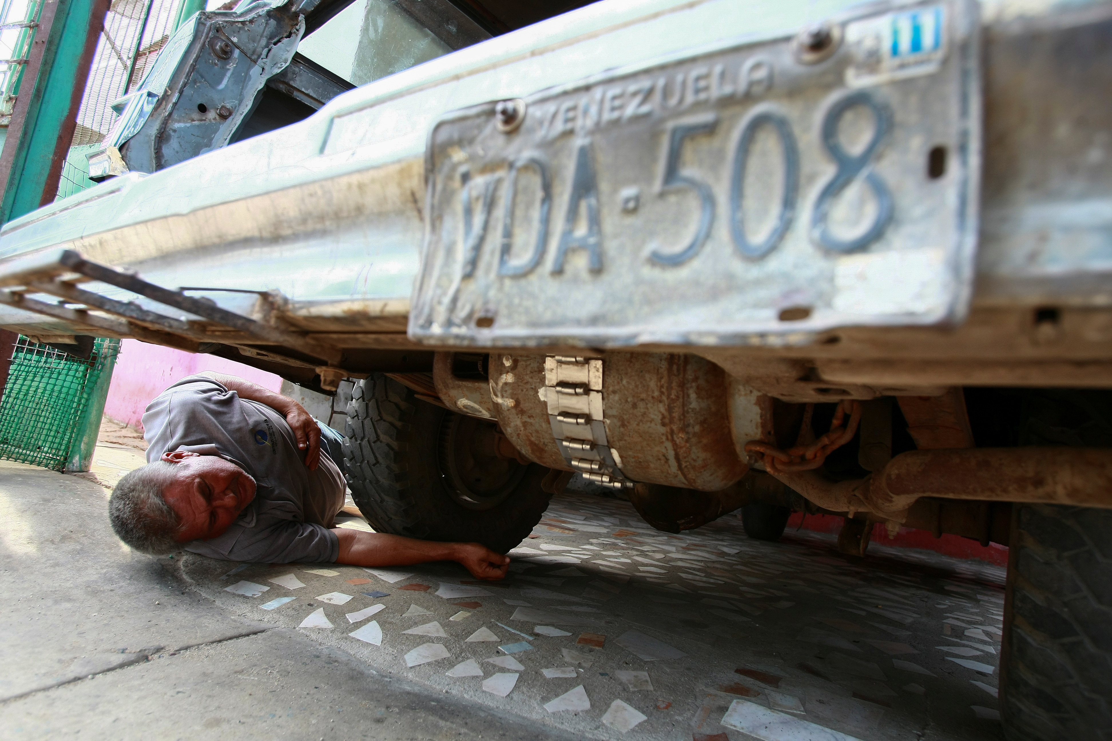 File photo: Alfredo Gonzalez checks a cooking gas canister beneath his car, which is used to run his vehicle instead of fuel, as Venezuelans are struggling to cope with chronic fuel shortage.