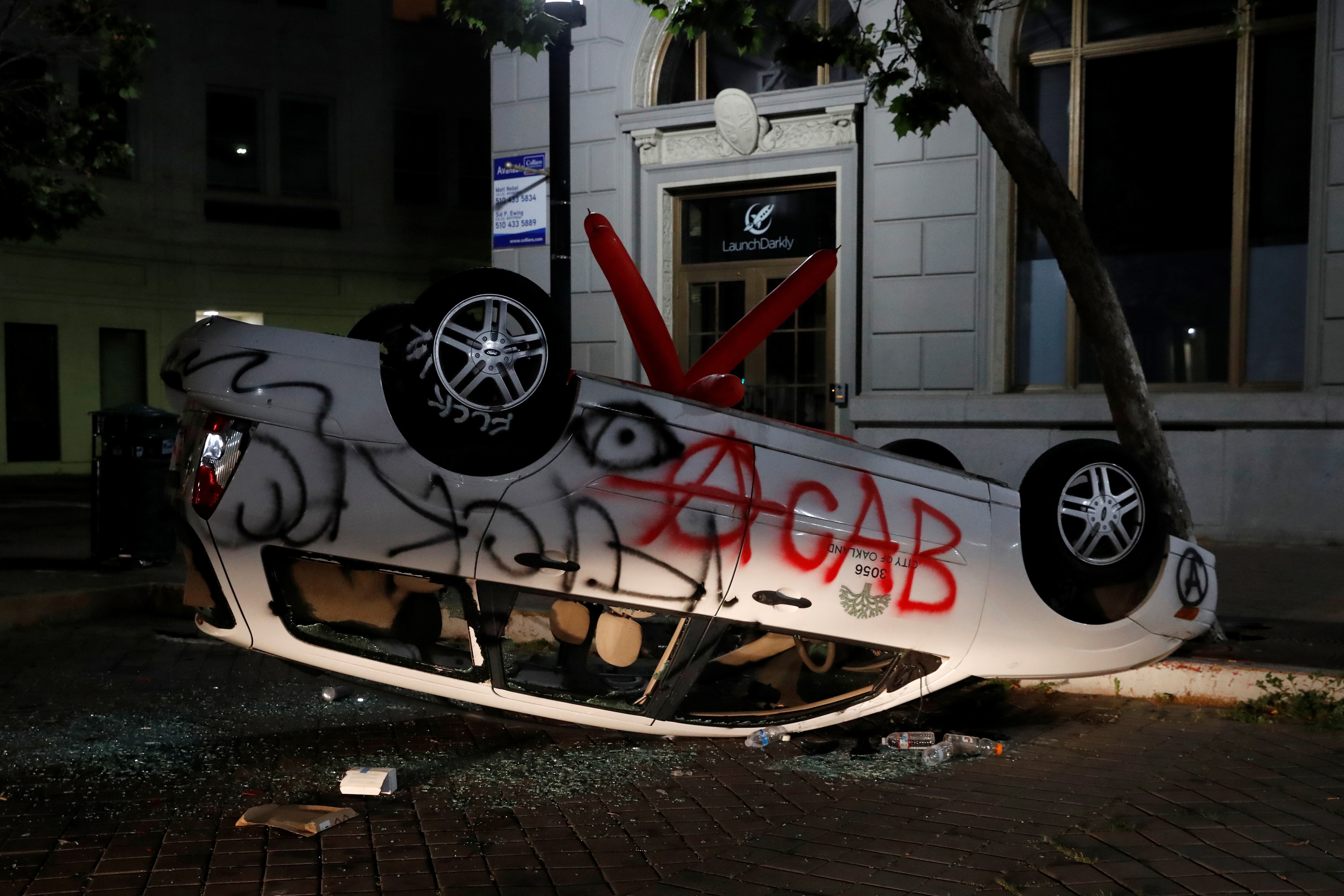 An overturned and vandalized City of Oakland vehicle is seen during a protest.