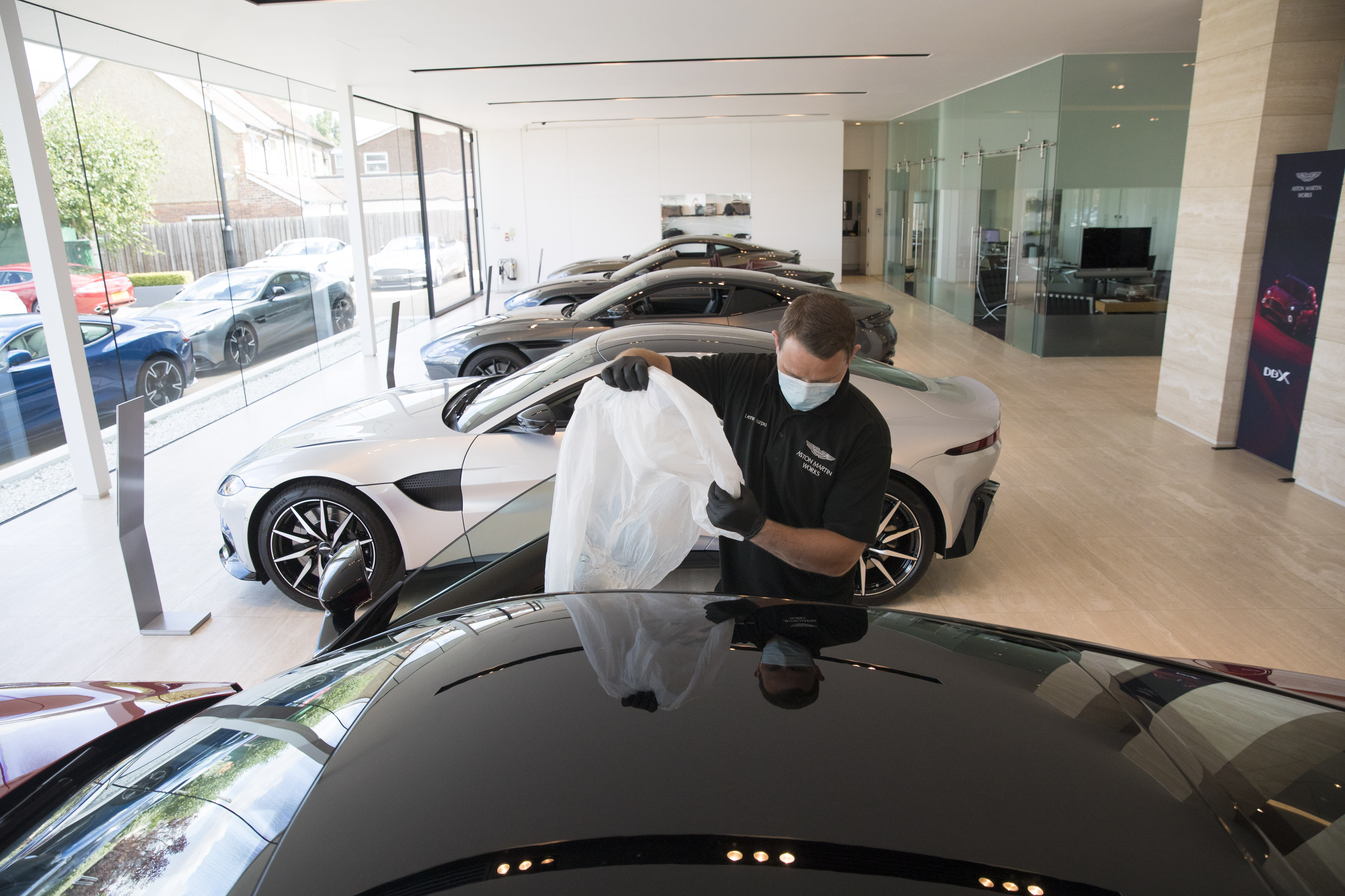 There are questions over whether normal business will resume even when the economy recovers. (File photo of a worker puts a plastic seat cover on an Aston Martin DBS).