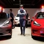 File photo: A man wearing a face mask following the coronavirus disease outbreak walks by Tesla Model 3 sedans and Tesla Model X sport utility vehicle at a new Tesla showroom in Shanghai, China  (REUTERS)