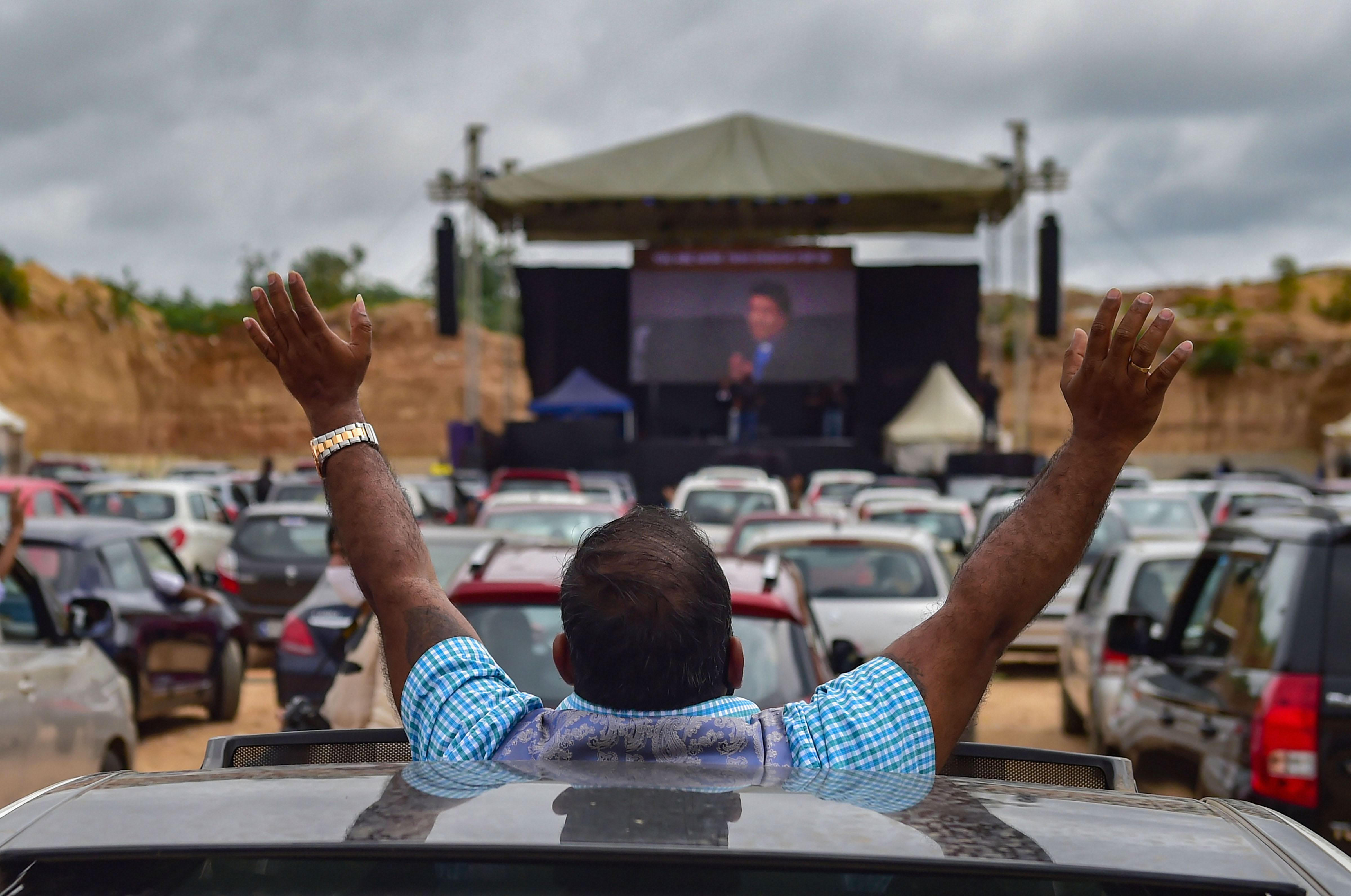 A priest addressed the congregation from the stage in an open plot where several cars lined up for the Sunday service. A priest addressed the congregation from the stage in an open plot where several cars lined up for the Sunday service.
