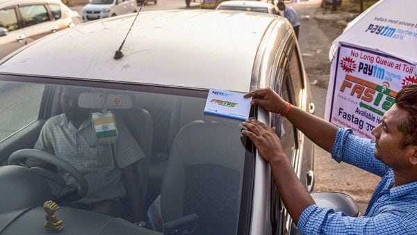 File photo of a worker fixing a FASTag sticker on the windscreen of a car, at Vashi Toll Plaza on Sion Panvel Highway, Mumbai. (PTI)