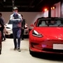 A man wearing a face mask following the coronavirus disease outbreak walks by Tesla Model 3 sedans and Tesla Model X sport utility vehicle at a new Tesla showroom in Shanghai, China. (REUTERS)
