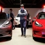 A man wearing a face mask following the coronavirus disease (COVID-19) outbreak walks by Tesla Model 3 sedans and Tesla Model X sport utility vehicle at a new Tesla showroom in Shanghai, China May 8, 2020.  (REUTERS)