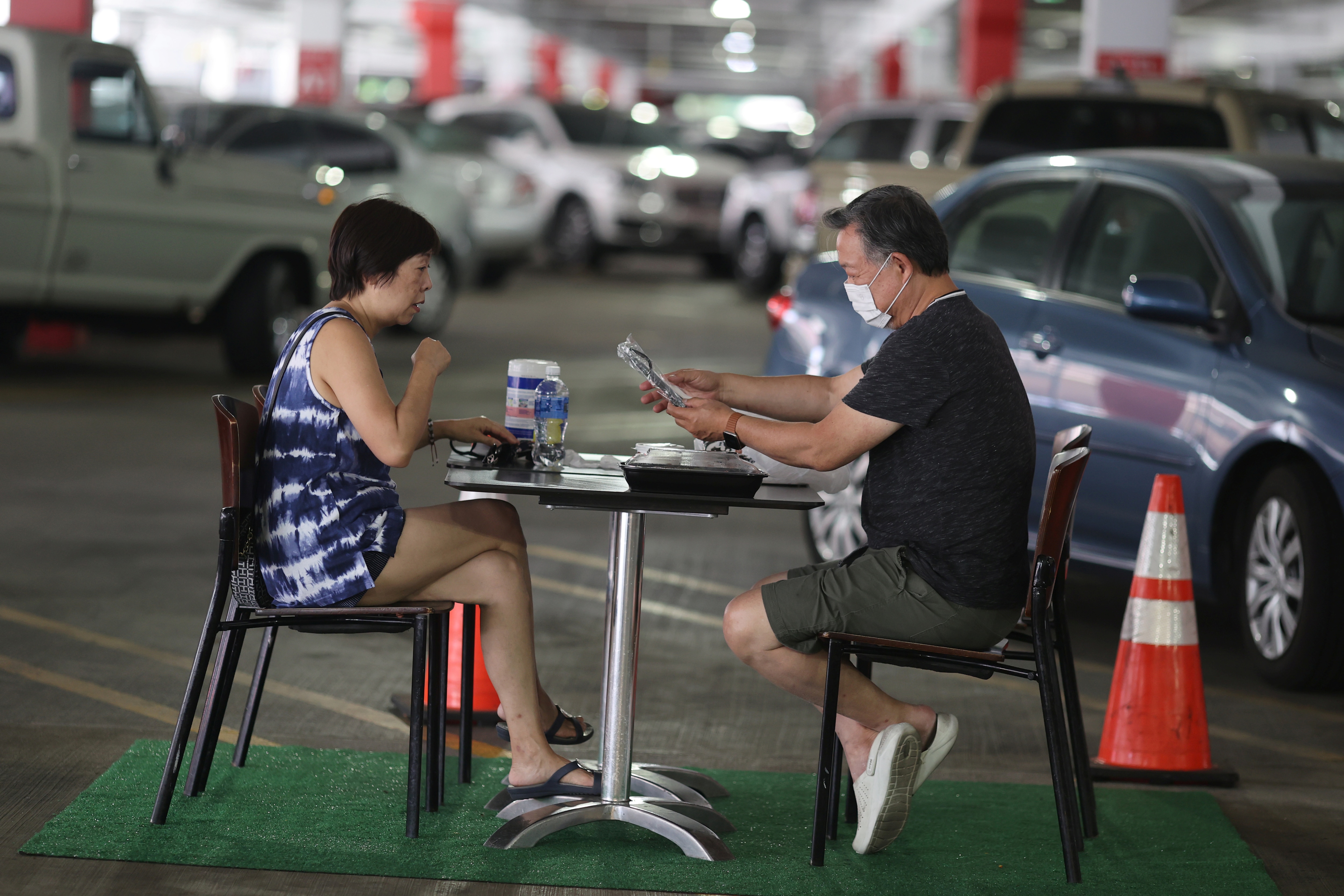 People eat lunch in a dining area set up in the Glendale Galleria mall parking garage.
