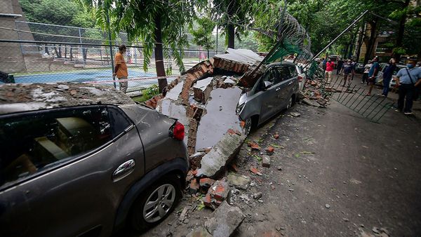 People look at damaged vehicles after wall of a public school collapsed due to heavy rains, at Saket in New Delhi. (PTI)