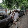 People look at damaged vehicles after wall of a public school collapsed due to heavy rains, at Saket in New Delhi. (PTI)