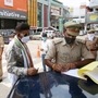 A police personnel fines a commuter in Noida for violating Covid-19 rules.