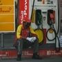 A petrol station worker wearing a facemask waits for customers while sitting next to a petrol pump.