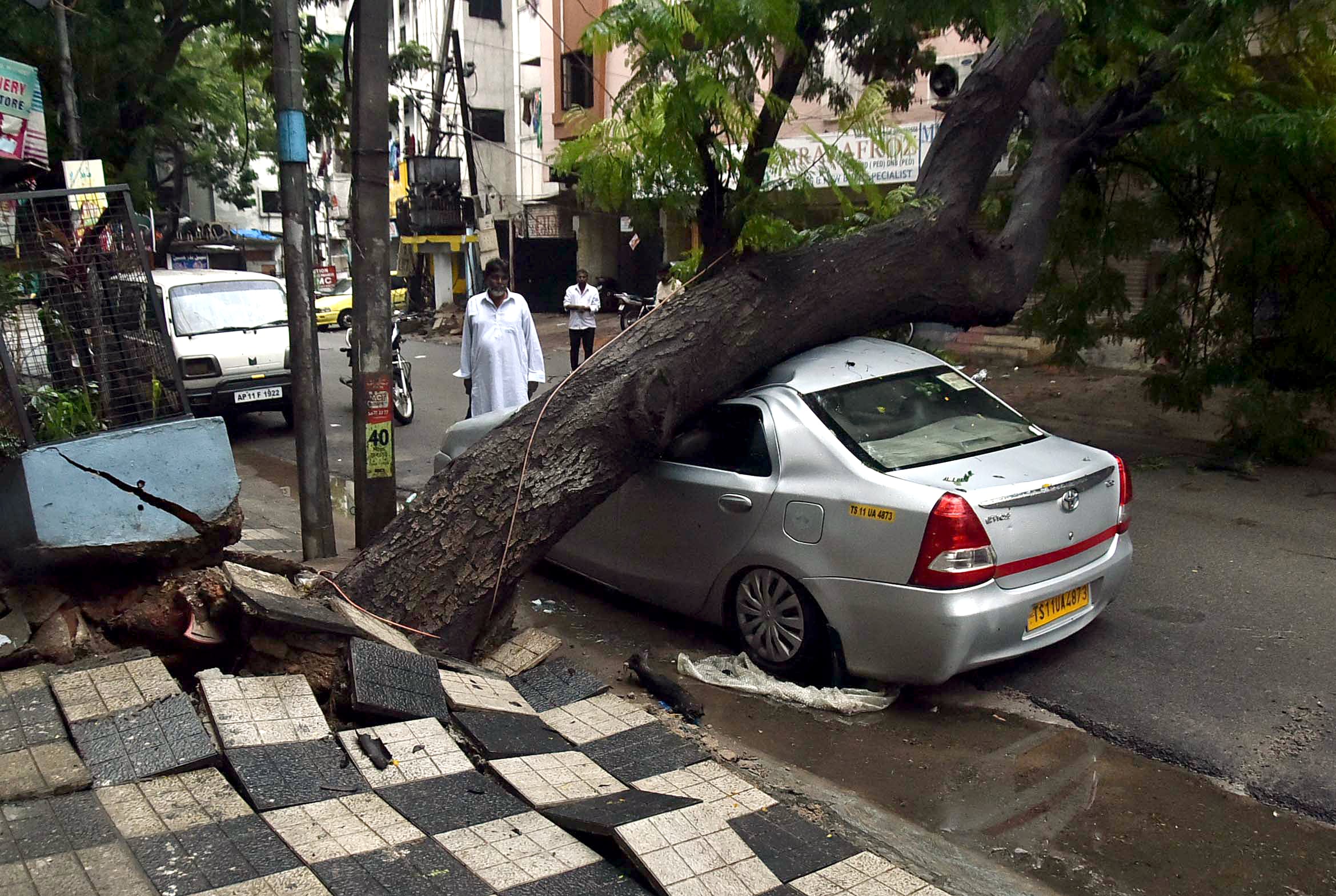 A tree fell down on a car at Noor khan Bazar after heavy rain in Hyderabad.