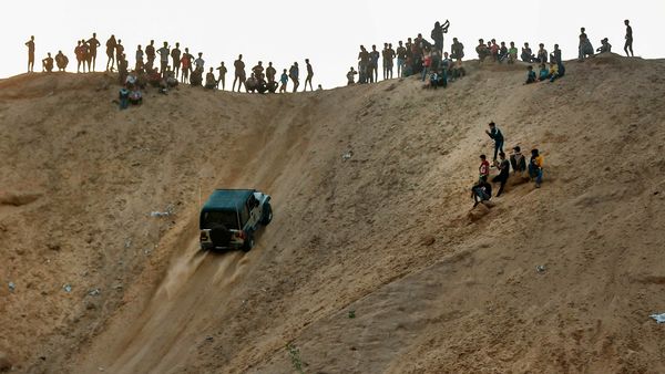 Spectators watch as a young Palestinian rides his jeep up a sandy hill during a weekly show in the Al-Zahra area near Gaza City.