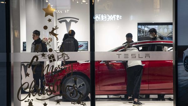 Shoppers and employees stand in a Tesla showroom in Shanghai, China. (Bloomberg)
