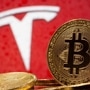 Representations of virtual currency Bitcoin are seen in front of Tesla logo in this illustration. (REUTERS)