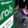 A woman uses her phone near a sign for the online ride-hailing service Grab at the Manggarai train station in Jakarta, Indonesia July 3, 2017. REUTERS/Agoes Rudianto/Files (REUTERS)