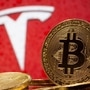 Representations of virtual currency Bitcoin are seen in front of Tesla logo. (REUTERS)
