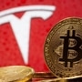 Representations of virtual currency Bitcoin are seen in front of Tesla logo. (REUTERS)