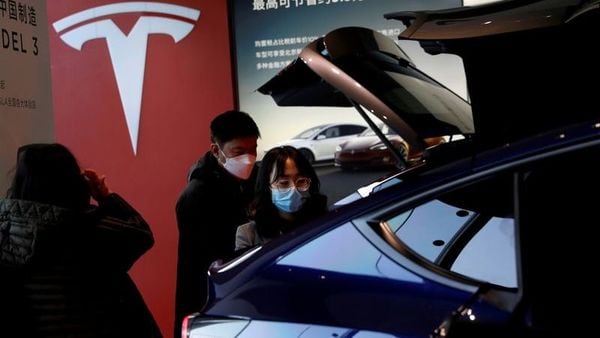 File photo: Visitors wearing face masks check a China-made Tesla Model Y sport utility vehicle (SUV) at the electric vehicle maker's showroom in Beijing. (REUTERS)